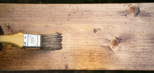 Wood processing.Cover the wooden board with a protective layer.A paint brush on a wooden background.