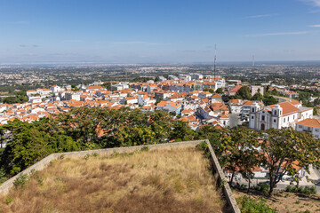 High angle aerial view of the town of Palmela, Portugal, seen from the castle. White buildings with red terracotta roofs spread out to the horizon.