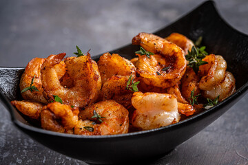 Spicy grilled shrimp with herbs in dark bowl