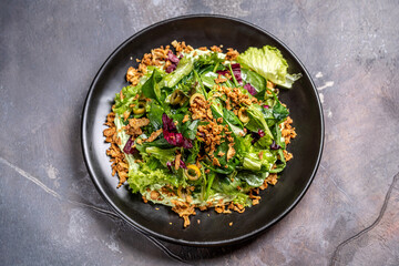 Fresh mixed salad with crispy toppings on black plate