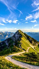 Obraz premium Sunny mountain peak scene with winding path and distant ranges beneath a bright blue sky