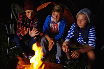 Campfire, night and smile with children outdoor together for adventure, bonding or survival hobby. Dark, flame and heat with group of happy kids camping for holiday, travel or vacation as friends