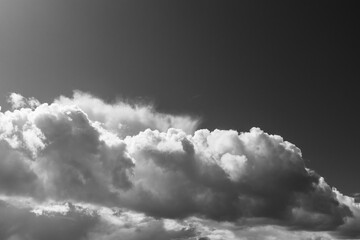 Monotone view of large billowing clouds rising against a dark sky