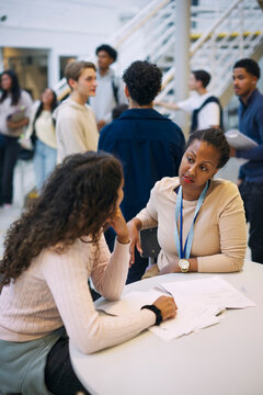 Female professor explaining educational test results to teenage student while sitting in high school lobby