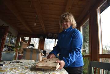 Woman holding a wooden cutting board in rustic kitchen