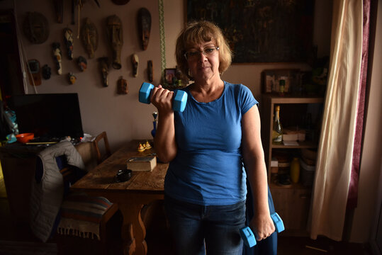 Woman exercising at home ndoors with blue dumbbells
