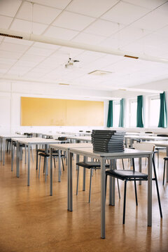 Stack of laptops kept on desk in empty classroom at high school building