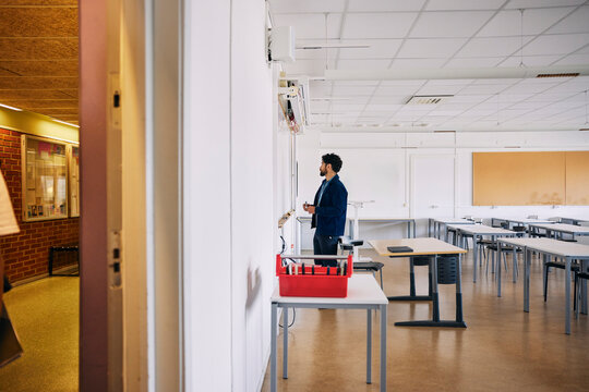 Male professor standing near whiteboard in empty classroom at high school