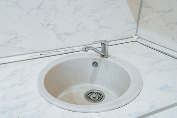 Contemporary kitchen with luxurious fixtures, Chic round basin with stylish chrome faucet detailing, Sophisticated interior setup featuring polished marble and minimalist highend fittings