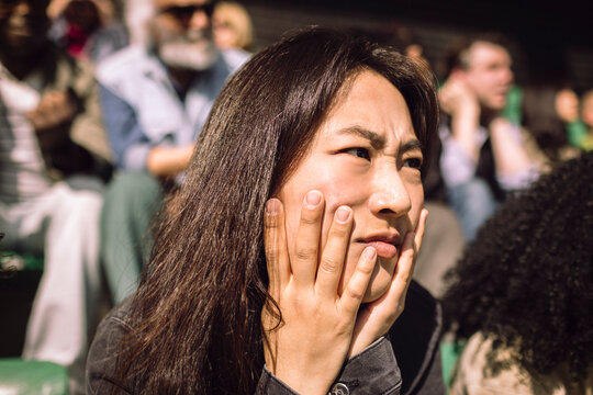 Displeased female fan watching game in stadium at sunny day