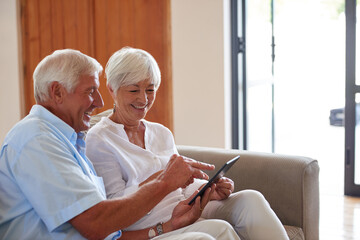 Obraz premium Streaming, smile and old couple on sofa with tablet, scroll or search for digital entertainment in retirement. Point, senior man or woman at house with tech, multimedia or online show in home.