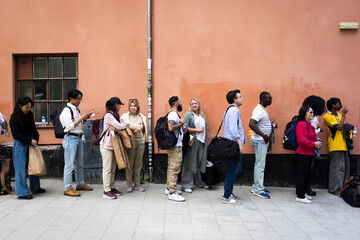 Male and female spectators waiting in line outside stage theater