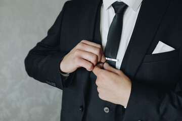 Groom adjusting tie clip before wedding