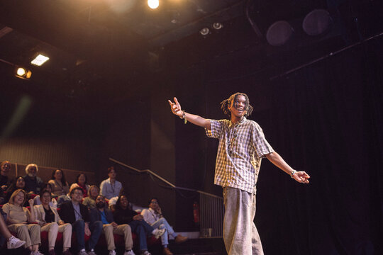 Low angle view of young male keynote speaker with braided hair gesturing while explaining in seminar at theater