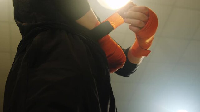 Sportsman wraps hands in bandages to protect muscles and joints. Man prepares to warm-up and uses elastic fabric to keep joints safe before workout