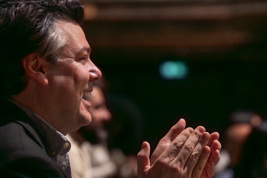 Headshot of happy mature man clapping in stage theater