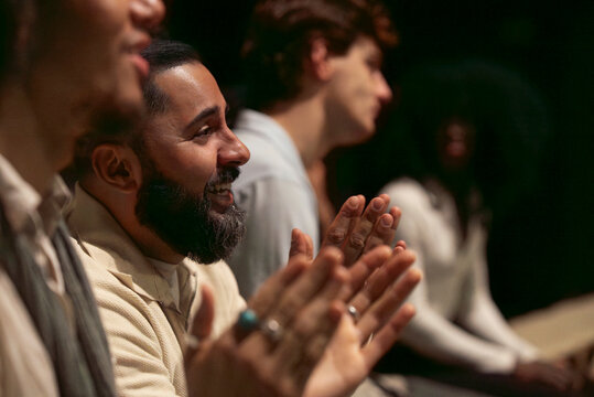 Happy bearded man clapping while enjoying play in stage theater