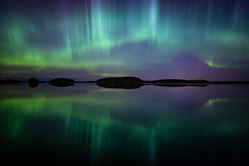 Amazing aurora borealis dancing over lake in Farnebofjarden national park in north of Sweden