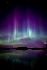 Amazing aurora borealis dancing over lake in Farnebofjarden national park in north of Sweden