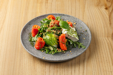Mixed green salad with featuring feta cheese, halved red peppers, green dressing.