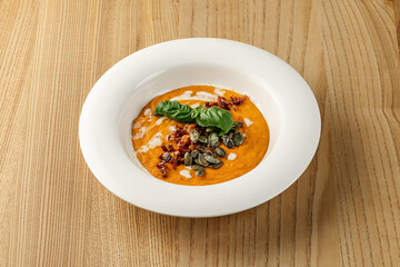The soup has a smooth, orange-red texture. A bowl of creamy tomato soup likely a gazpacho. 