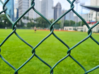 Sports field foreground fence with Jakarta skyscrapers