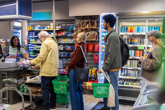 Male and female customers waiting in line for checkout after shopping in grocery store