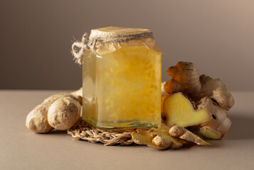 Ginger jam in small square jar and fresh ginger.