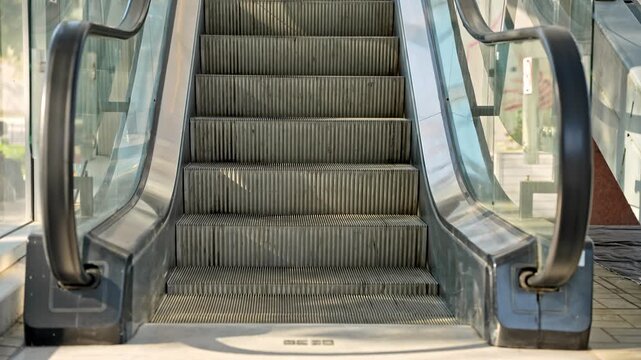 Close up view of moving escalator steps going upward with metallic texture and modern design, static camera shot.