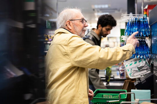 Senior man using self checkout machine in grocery store