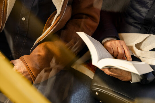 High angle midsection of man holding book while sitting beside father in bus