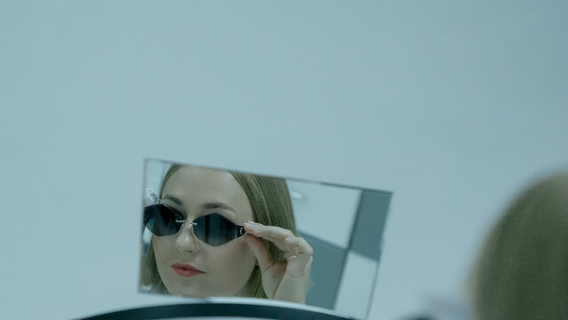 Woman gazes at her reflection in mirror in glasses