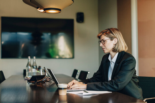 Short haired businesswoman working on laptop while sitting at table in law office