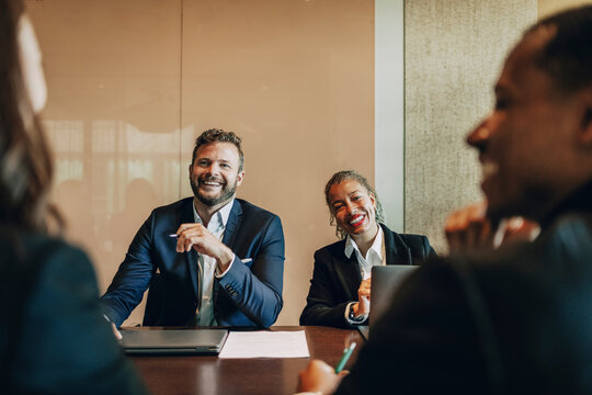Happy male and female law experts sitting in meeting room at office