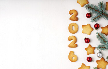 A cheerful holiday scene featuring cookies shaped into the digits 2026 on a white table, surrounded by evergreen sprigs and festive ornaments, perfect for Christmas, New Year