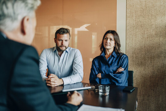Couple listening to male divorce lawyer explaining prenuptial agreement rules while sitting in office