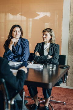 Woman sitting with divorce attorneys while discussing prenuptial agreement in office