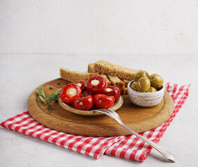 Red cherry peppers stuffed with cheese and olives on the wooden board o white table, copy space. Great snack.