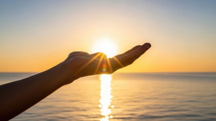 Hand reaching out to catch the golden sunlight over the ocean at sunrise