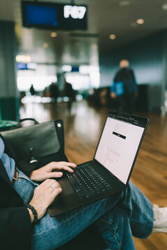 Midsection of female freelancer working on laptop while sitting at airport terminal