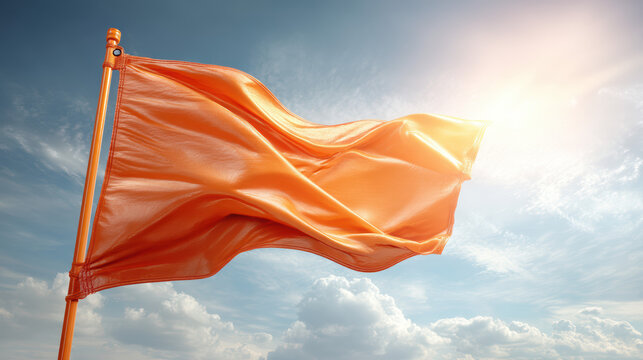An orange flag flutters prominently against a bright blue sky filled with soft white clouds on a sunny day, catching the light and drawing the eye upwards now.
