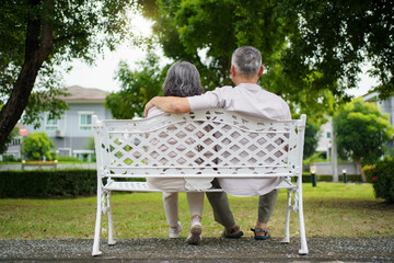 Fototapeta premium Elderly couple sitting together on a bench enjoying peaceful outdoor time.