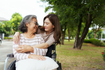 Naklejka premium Young woman hugging and caring for elderly woman in a wheelchair.