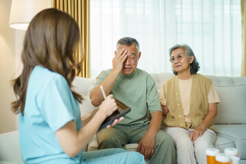 Elderly man consulting with nurse at home while his wife supports him.