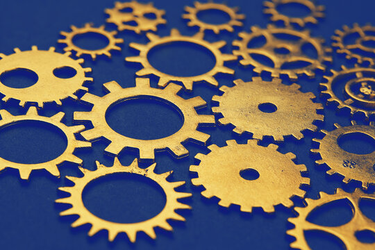Golden gears mechanism on dark blue background symbolizing teamwork - Powered by Adobe