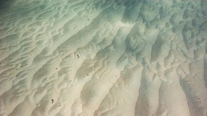 Abstract underwater shot of sandy seabed with dappling sunlight