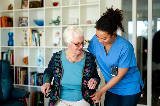 Smiling female healthcare expert helping senior woman sitting on rollator at home