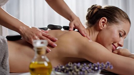Woman receiving hot stone massage therapy at a tranquil spa for relaxation and wellness - Powered by Adobe