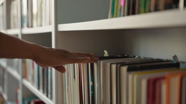 Close up African American man male hand choosing book in library touching bookshelf unknown student learner university reading literature textbooks bookcase education studying buyer hobby knowledge