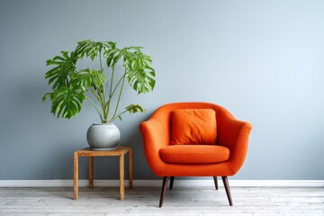 Orange armchair and potted plant against a gray wall.